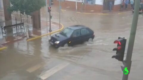 Un coche atravesando una calle de humilladero tras la tormenta Un coche atravesando una calle de humilladero tras la tormenta