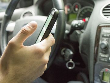 Imagen de archivo de un conductor usando el móvil al volante Imagen de archivo de un conductor usando el móvil al volante