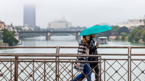 Dos personas atraviesan el puente de San Telmo, con el puente de Triana y Torre Sevilla. Dos personas atraviesan el puente de San Telmo, con el puente de Triana y Torre Sevilla.