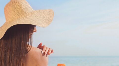 Mujer echándose crema solar en la playa Mujer echándose crema solar en la playa