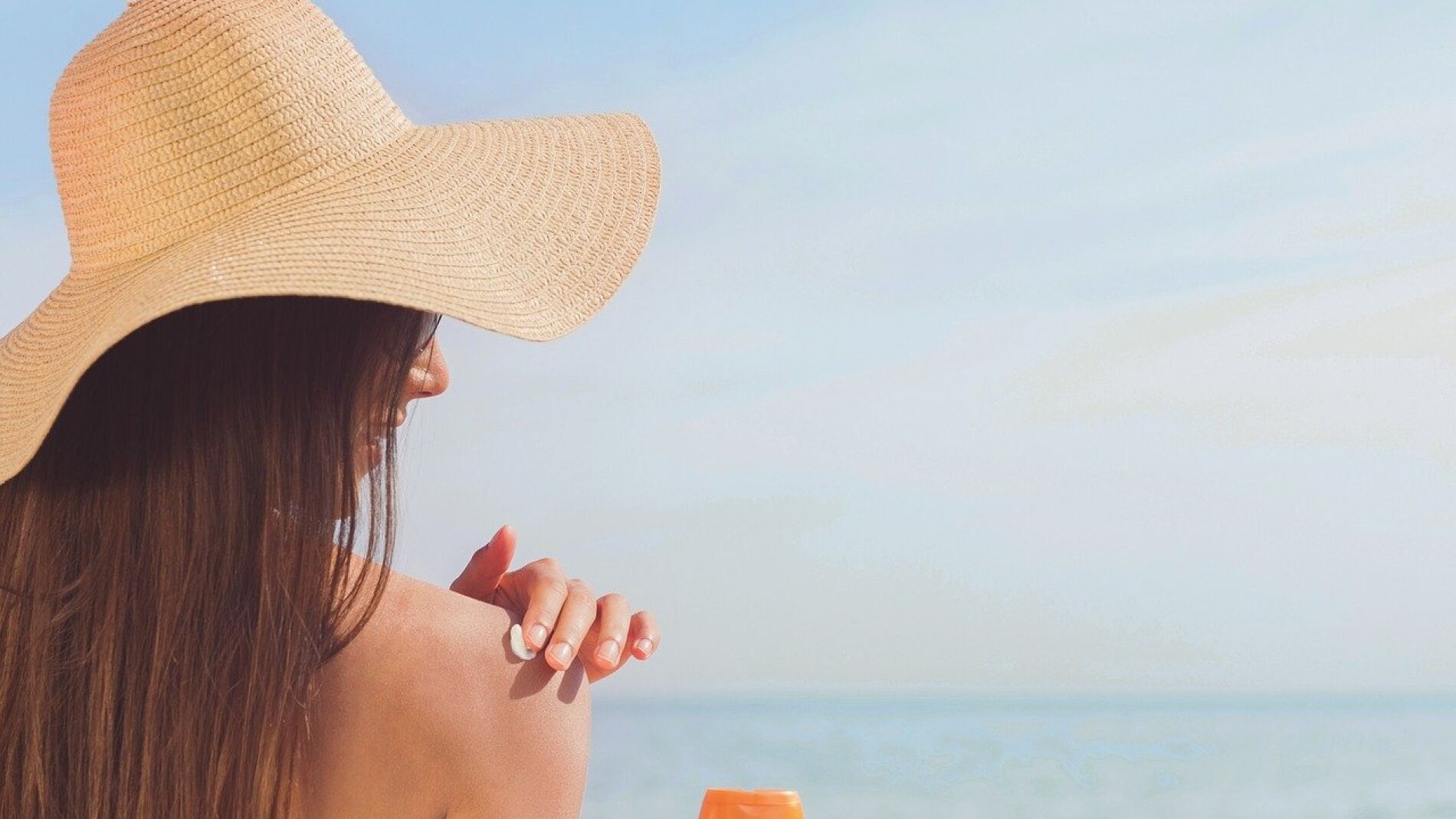 Mujer echándose crema solar en la playa