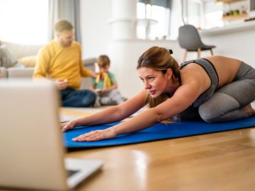 mujer haciendo ejercicio en casa con su familia detrás