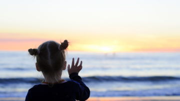 Una niña se despide del sol en una playa