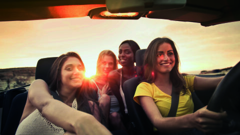 Grupo de amigas en descapotable al atardecer