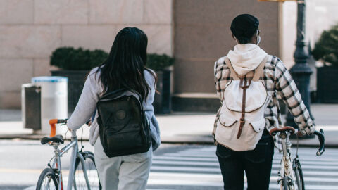 Dos ciclistas cruzan a pie con sus bicis un paso de peatones