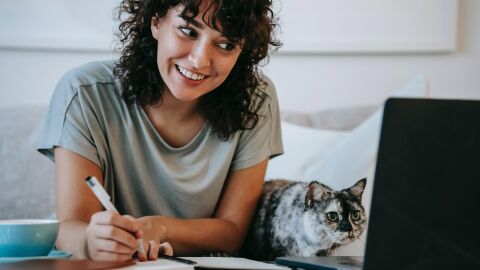 Mujer teletrabajando con un gato en la mesa