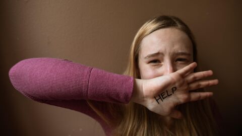 Adolescente con la palabra "help" escrita en la mano