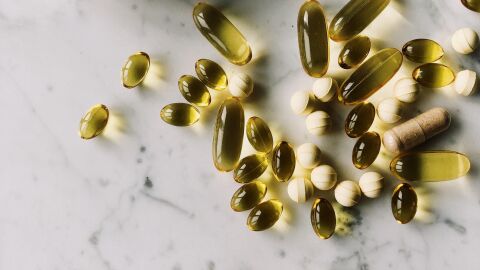 Capsulas y pastillas de complementos alimenticios sobre una superficie de m&aacute;rmol jaspeada