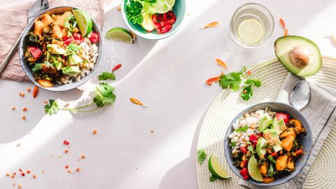 Diferentes boles con ensaladas variadas, aguacate y un vaso de agua con lim&oacute;n 