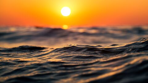 Primer plano de olas del océano al atardecer con tonos cálidos de naranja, capturando la serenidad y la belleza de la naturaleza Primer plano de olas del océano al atardecer con tonos cálidos de naranja, capturando la serenidad y la belleza de la naturaleza