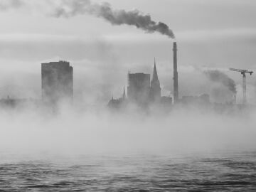 Paisaje urbano monocromático con niebla y chimeneas industriales sobre el agua. Paisaje urbano monocromático con niebla y chimeneas industriales sobre el agua.