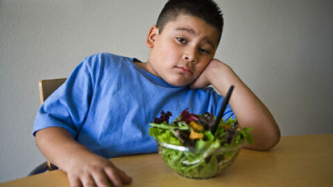 Niño obeso con una ensalada Niño obeso con una ensalada