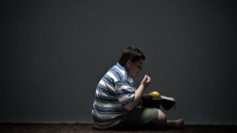 Niño con problemas de obesidad comiendo Niño con problemas de obesidad comiendo