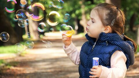 Una niña hace pompas de jabón Una niña hace pompas de jabón