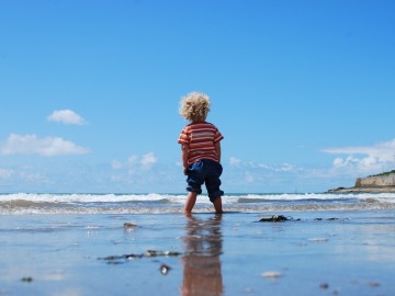 Un niño pequeño pasea en por la playa