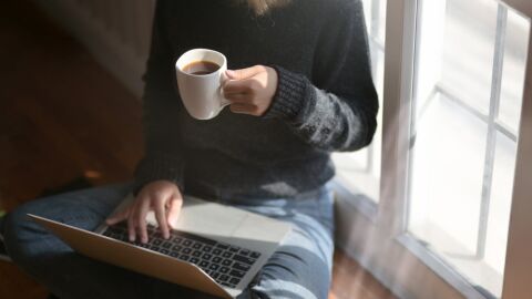 Una mujer bebiendo café y usando el portátil Una mujer bebiendo café y usando el portátil