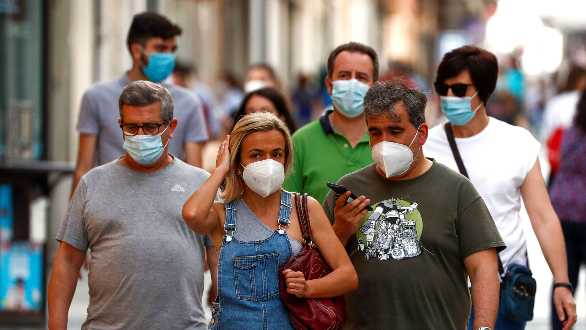 Ciudadanos pasean por la calle protegidos con mascarillas