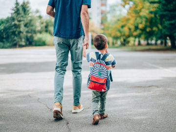 Un padre camina con su hijo en direcci&oacute;n al colegio