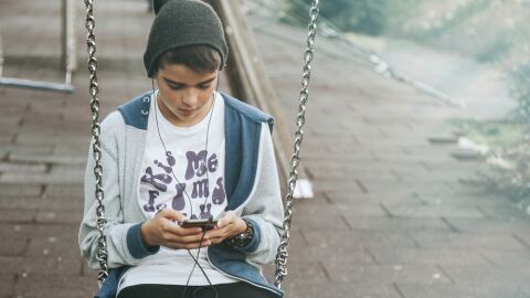 Un niño consulta su móvil en un parque