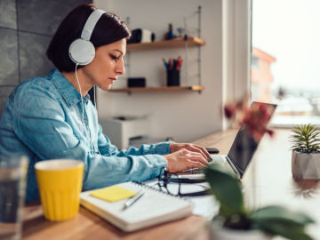 Una mujer teletrabaja desde su casa con los auriculares puestos