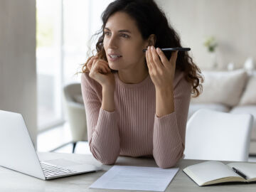 Una mujer escucha un audio en su tel&eacute;fono m&oacute;vil mientras trabaja