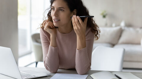 Una mujer escucha un audio en su tel&eacute;fono m&oacute;vil mientras trabaja