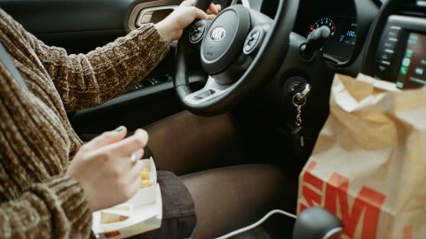 Comer y beber al volante son incompatibles con la conducción Mujer comiendo en el coche