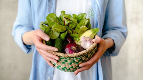 Mujer sostiene cesta con alimentos frescos
