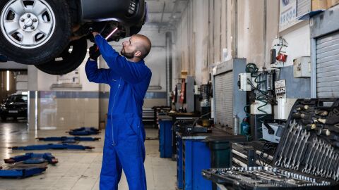 Coche revisado por mec&aacute;nico en un taller