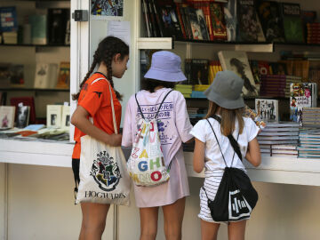 Tres ni&ntilde;as visitas una caseta de la Feria del Libro de Madrid. 