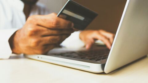 Una persona, haciendo una compra por internet con su tarjeta bancaria.