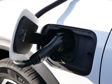 Vista en primer plano de un veh&iacute;culo el&eacute;ctrico carg&aacute;ndose, con especial atenci&oacute;n al conector y al puerto de carga